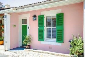 A building with a pink facade, green shutters, and a number '2' sign.
