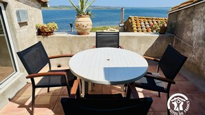 A patio with a round table and four chairs, overlooking a body of water. - Nature Sauvage Méditerranée (BAGES)