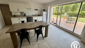 A modern kitchen with white cabinets, a dining table with chairs, and a large sliding glass door leading to an outdoor patio.
