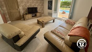 A living room with a sofa, a coffee table, and a TV on a wooden stand.