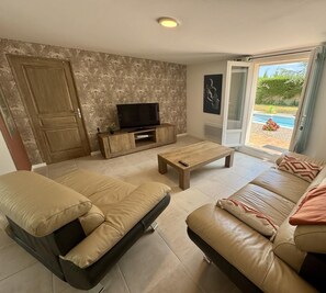 A living room with a sofa, a coffee table, and a TV on a wooden stand. - Les 3 Tours - 2 - ROULLENS (ROULLENS)