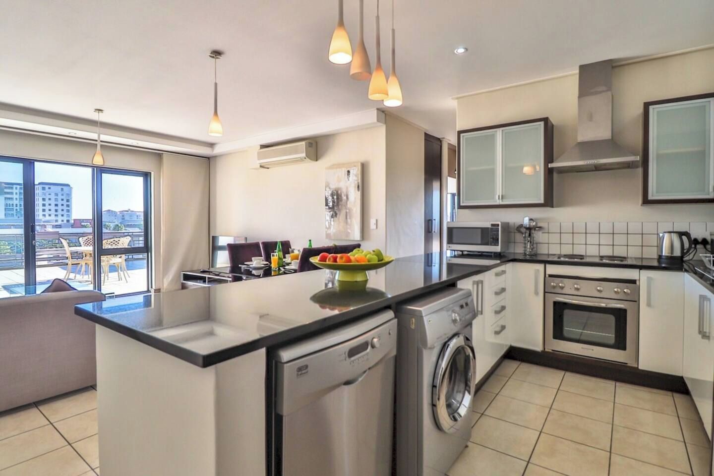 A modern kitchen with a central island, built-in appliances, and pendant lighting.