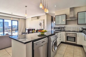 A modern kitchen with a central island, built-in appliances, and pendant lighting.