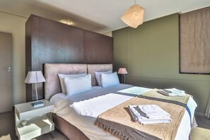 A hotel room with a large bed, bedside tables, a lamp, and a wall-mounted light fixture.