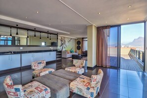 A modern living area with a kitchen, dining set, and a balcony with a view.
