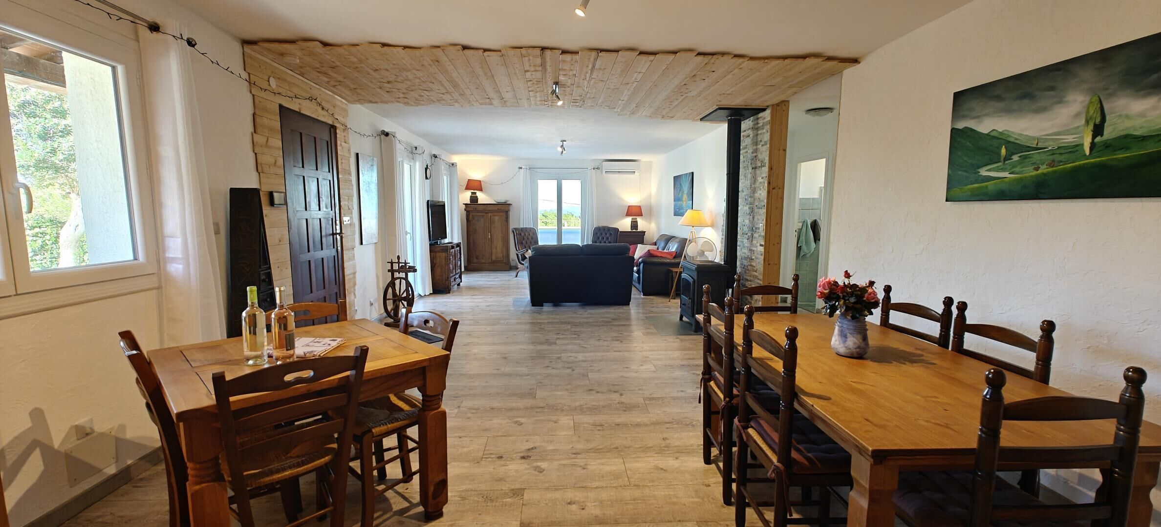 Un comedor amplio con mesas y sillas de madera, una chimenea central y vistas al exterior.