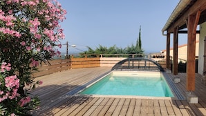 Eine Holzterrasse mit Swimmingpool, umgeben von Holzgeländern und einer Pergola.