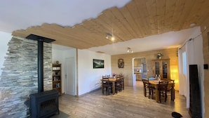 Ein gemütliches Wohnzimmer mit Kamin aus Stein, Holzboden und einem Essbereich mit Holztisch und -stühlen.
