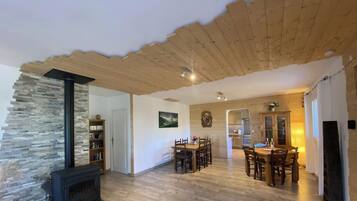 Una sala de estar acogedora con chimenea de piedra, techo de madera y comedor con mesa y sillas de madera.