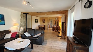 Ein gemütliches Wohnzimmer mit Ledersofa, Couchtisch und Fernseher. Im Hintergrund ist eine Essecke mit Tisch und Stühlen zu sehen.