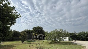 A grassy area with a swing set and trees.