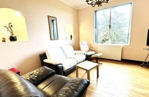 A living room with a sofa, armchair, coffee table, and a TV on a stand.