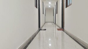 A long, narrow hallway with white walls and a shiny, cracked floor.