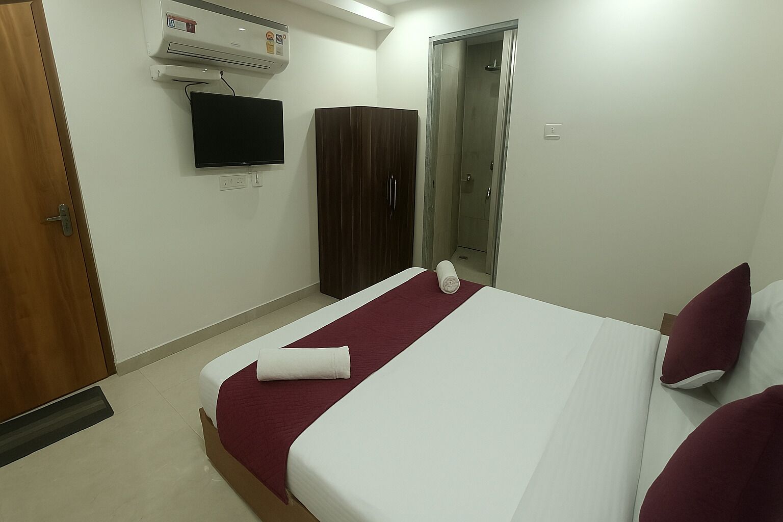 Een hotelkamer met een bed, een aan de muur bevestigde televisie, een kast en een douche.