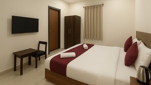 A hotel room with a bed, a TV mounted on the wall, a desk, and a wardrobe.