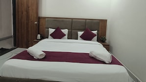A modern hotel room with a large bed, a wooden wardrobe, and a marble floor.