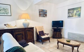 Ein Wohnzimmer mit einer Couch, einem Sessel, einem Fernseher und einem Tisch.