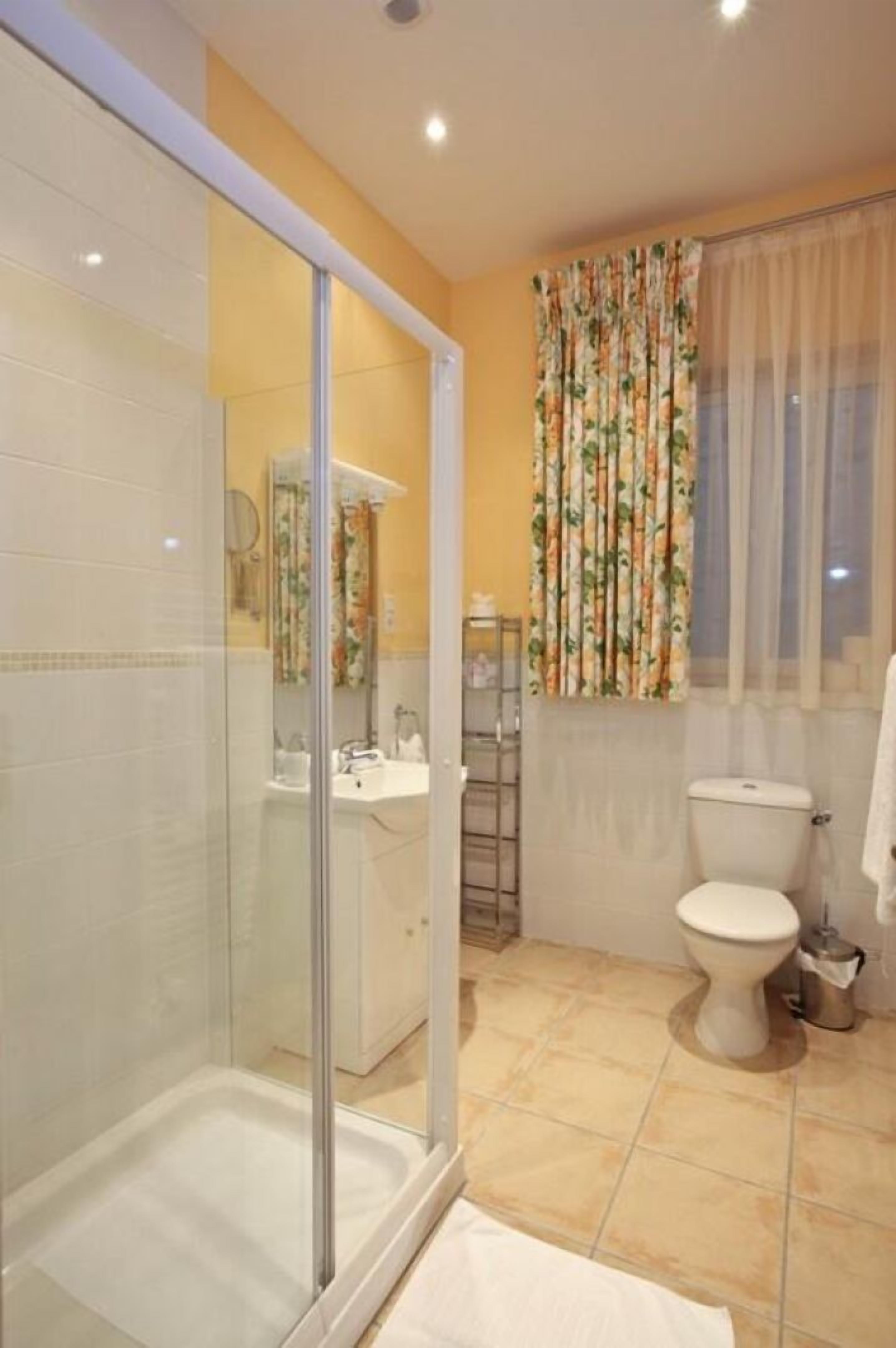 Une salle de bain avec une douche à parois de verre, des toilettes et un lavabo.