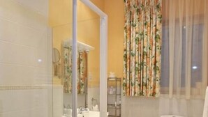 Een badkamer met een glazen douchecabine, toilet en wastafel.