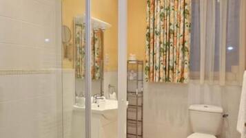 Une salle de bain avec une douche à parois de verre, des toilettes et un lavabo.
