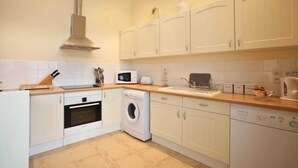 Een compacte keuken met witte kastjes, een magnetron, een broodrooster, een spoelbak en een wasmachine.