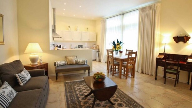 Een woonkamer met een bank, een salontafel en een eethoek met een tafel en stoelen.