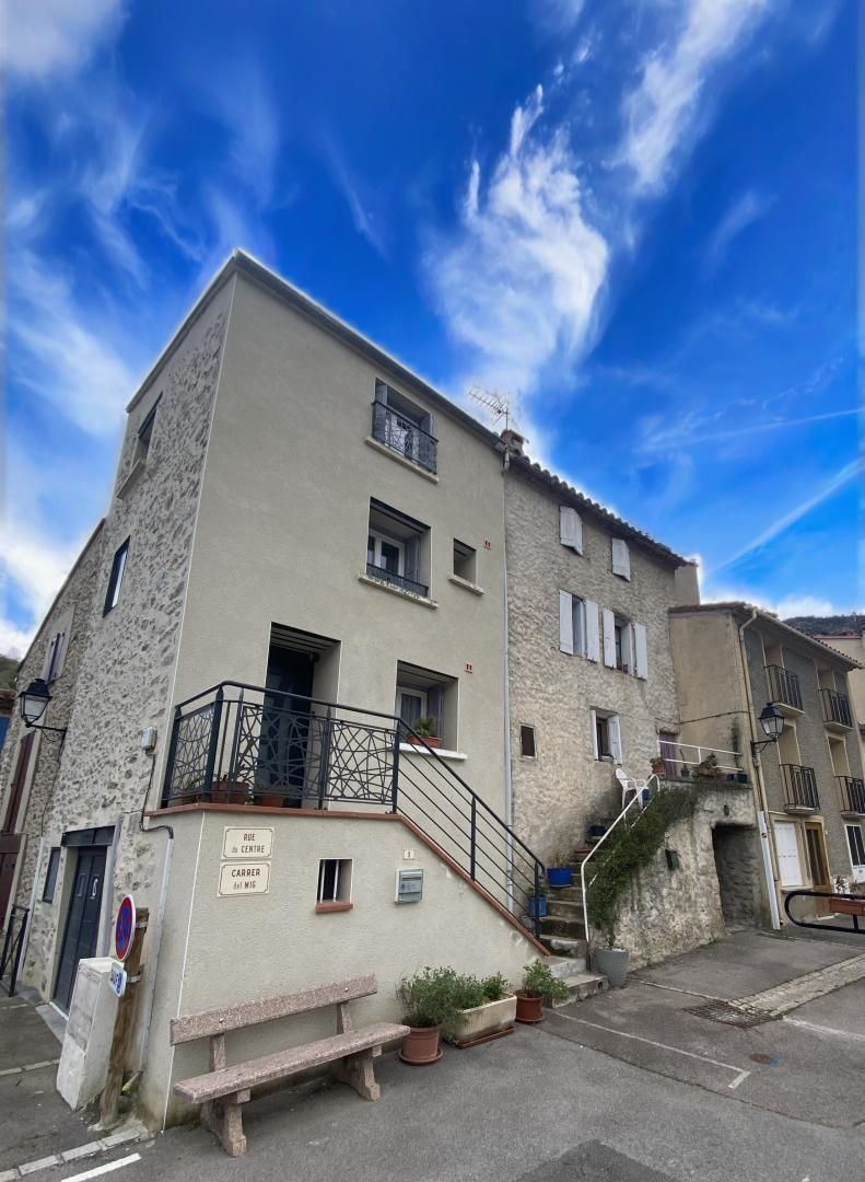 Un immeuble à plusieurs étages, doté d’une façade en pierre, d’un balcon orné d’une balustrade en fer forgé et d’une enseigne indiquant « Rue du Centre ».