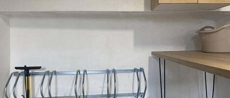 Une cuisine dotée d’un plan de travail en bois, d’une étagère suspendue pour ranger les ustensiles et d’un outil de nettoyage jaune.