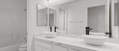 A modern bathroom with a white vanity, two sinks, a large mirror, and a shower area.