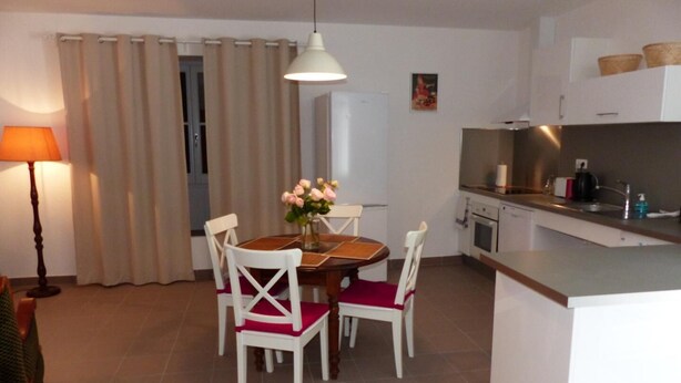Eine kompakte Küche mit Essbereich, ausgestattet mit einem Tisch, Stühlen, einer Hängelampe und einem Kühlschrank.