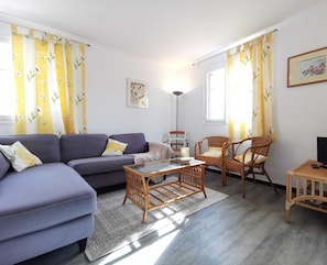 Una sala de estar con un sofá, sillas, una mesa de centro y un televisor.