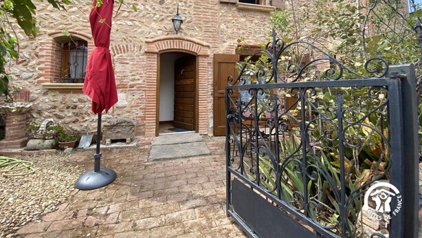 A stone building with a wooden door and a metal gate. - Dona Lucrècia - PONTEILLA (PONTEILLA)