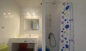 A bathroom with a white sink, mirror, and shower curtain with a polka dot pattern.