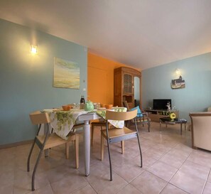 A dining area with a table set for four, a television, and a sofa in a living room.