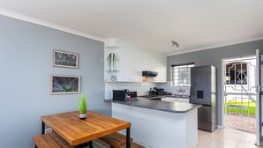 Una cucina moderna con tavolo da pranzo in legno, pensili bianchi e isola integrata.