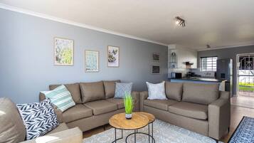 A modern living room with a sofa set, a coffee table, and artwork on the wall.