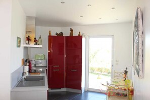 A kitchen with a sink, a coffee maker, and a red cabinet. - Les Cycas - PONTEILLA (PONTEILLA)