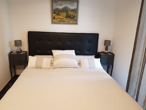 A hotel room with a large bed, two bedside tables, and a painting on the wall.