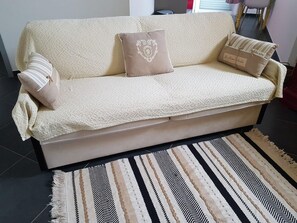 A beige sofa with a textured throw blanket and decorative pillows.