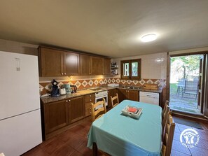 A compact kitchen with wooden cabinets, a built-in oven, and a dining area with a table.
