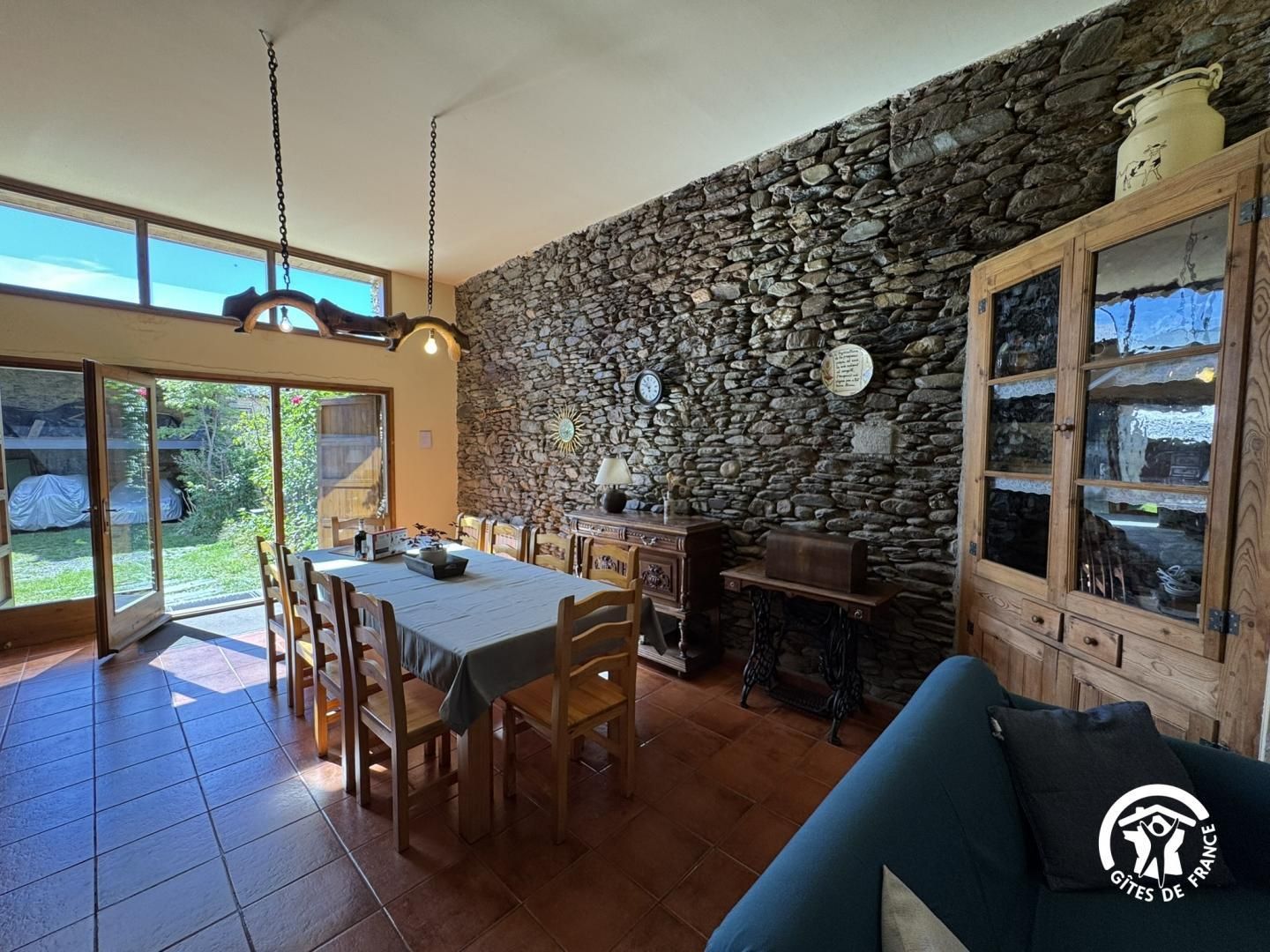 A dining area with a stone wall, wooden furniture, and a view through the glass doors.