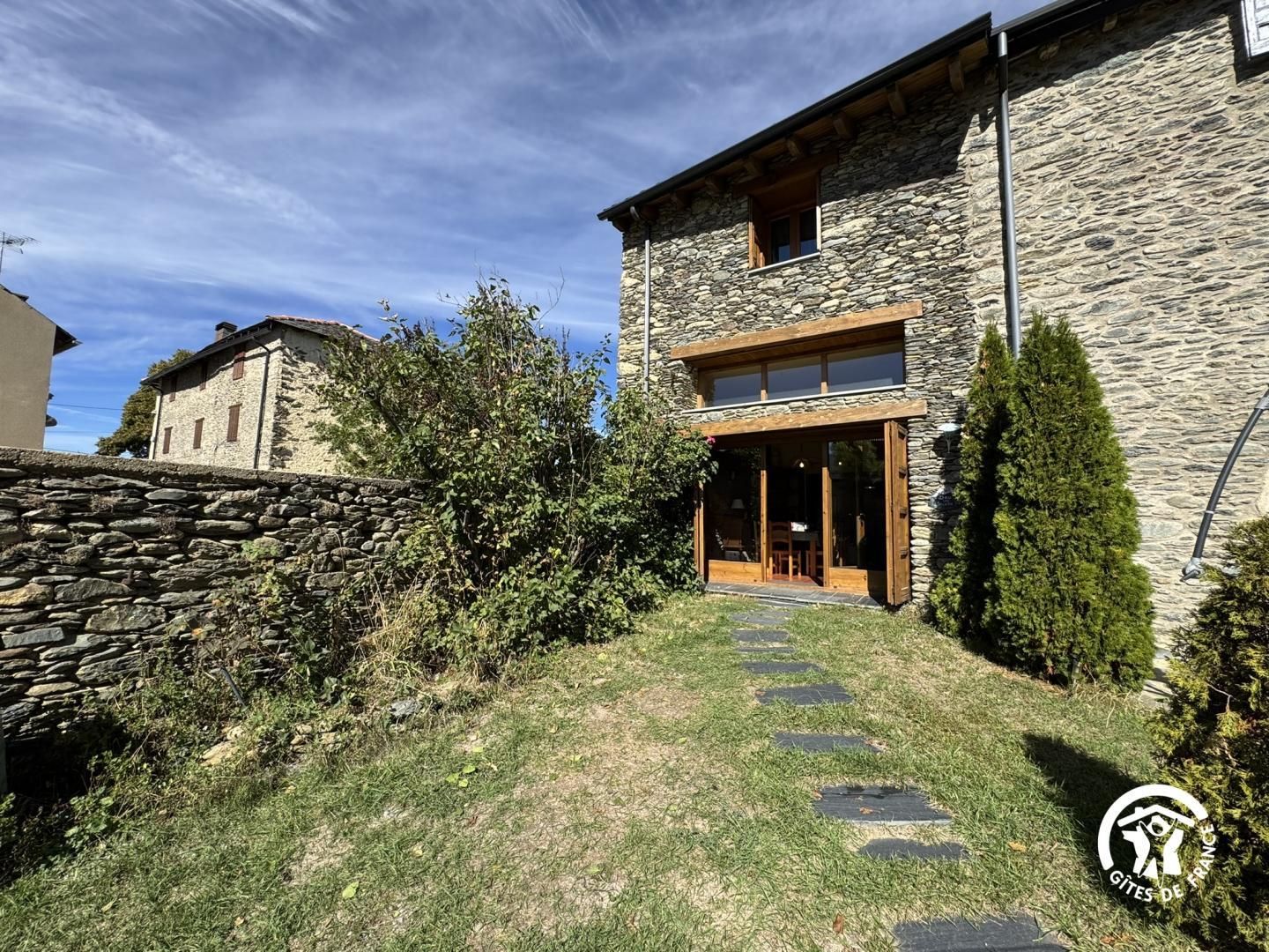 A stone building with a wooden porch and a stone wall.