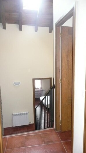 A staircase with a wooden door at the top, a radiator on the wall, and a small window.