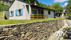 A single-story house with a stone wall in front, a wooden fence, and a clear sky. - Nore & Nature - PRADELLES CABARDES (PRADELLES CABARDES)