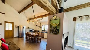 A spacious living area with a wooden ceiling, a dining table, and a kitchen in the background. - Nore & Nature - PRADELLES CABARDES (PRADELLES CABARDES)