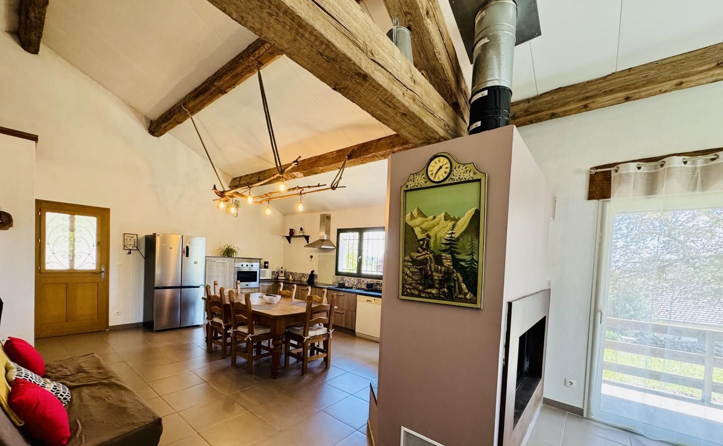 Amplia sala de estar con techo de madera, una mesa de comedor y una cocina al fondo.