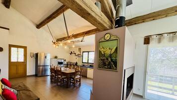 Amplia sala de estar con techo de madera, una mesa de comedor y una cocina al fondo.