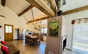 A spacious living area with a wooden ceiling, a dining table, and a kitchen in the background. - Nore & Nature - PRADELLES CABARDES (PRADELLES CABARDES)