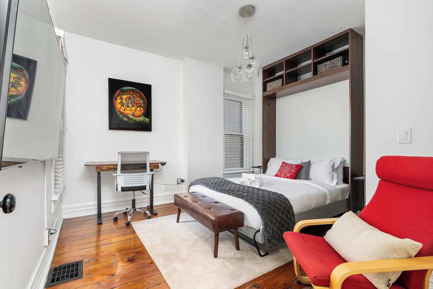 Une chambre à coucher moderne avec un lit, un bureau, une chaise et un fauteuil rouge.