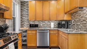 A modern kitchen with wooden cabinets, stainless steel appliances, and a patterned backsplash. - *NEW* Walk 2 Short North | Hot Tub | Easy Parking (Columbus)